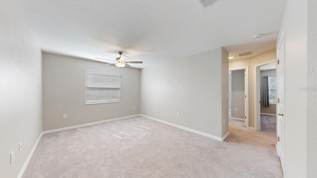 spare room featuring light carpet, a textured ceiling, and ceiling fan