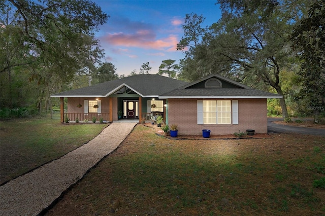 ranch-style house featuring covered porch and a yard