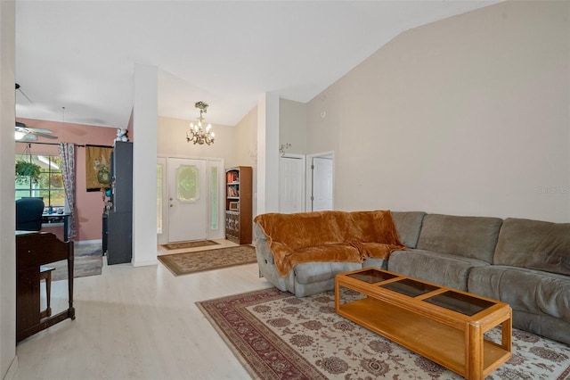 living room featuring light hardwood / wood-style floors, ceiling fan with notable chandelier, and lofted ceiling