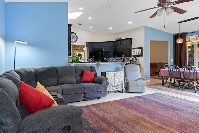 living room featuring vaulted ceiling, ceiling fan, and light hardwood / wood-style flooring