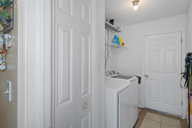 laundry area with a textured ceiling, light tile patterned floors, and washer and dryer