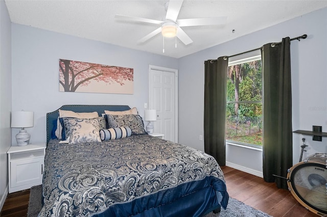 bedroom with dark wood-type flooring, ceiling fan, multiple windows, and a textured ceiling