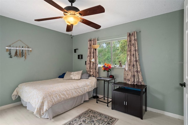 bedroom featuring light hardwood / wood-style floors, ceiling fan, and a textured ceiling