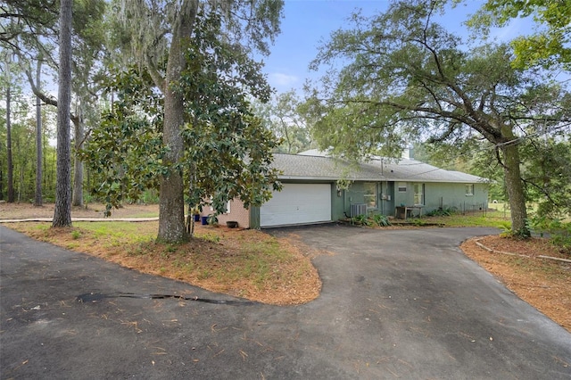 single story home featuring a garage and aphalt driveway