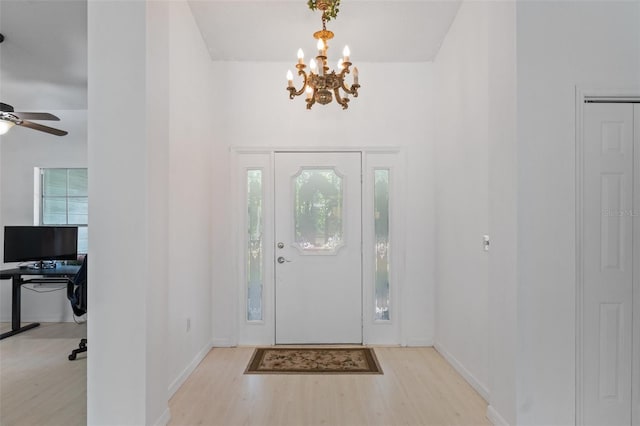entrance foyer featuring ceiling fan with notable chandelier, baseboards, and wood finished floors