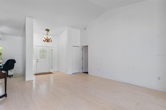 foyer entrance featuring a healthy amount of sunlight, high vaulted ceiling, a chandelier, and light wood-type flooring