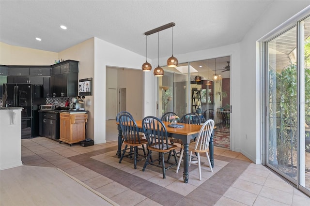 dining room featuring light tile patterned floors, lofted ceiling, and a textured ceiling