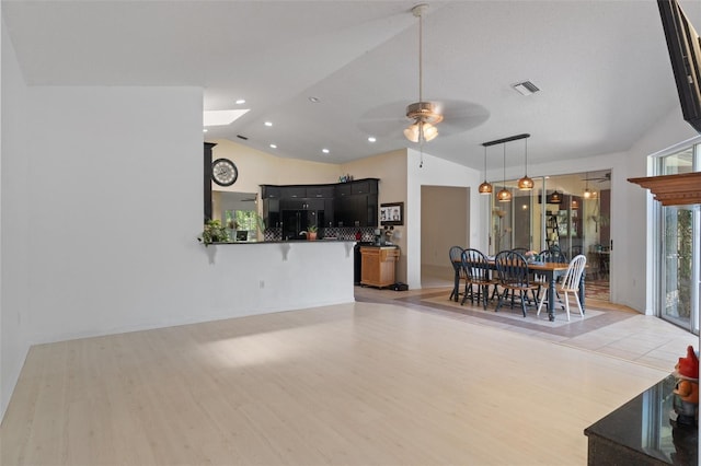 living area with visible vents, light wood-style floors, lofted ceiling, and a ceiling fan