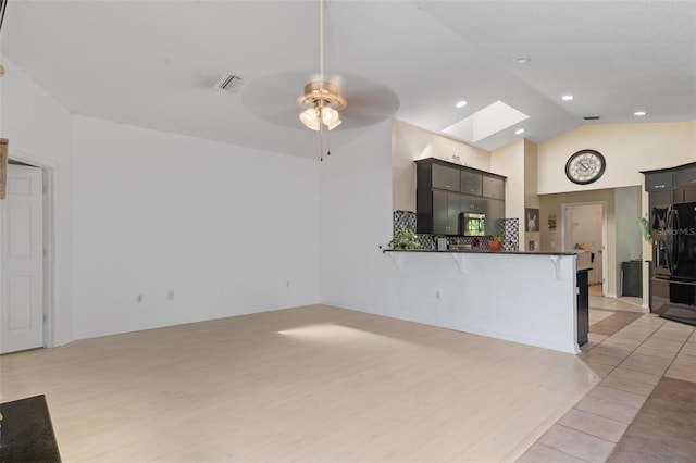 living area with light wood-style flooring, a skylight, ceiling fan, and visible vents