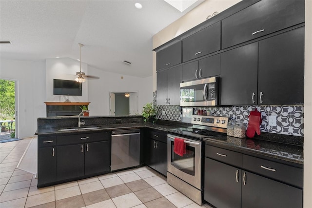 kitchen featuring light tile patterned flooring, vaulted ceiling, a sink, appliances with stainless steel finishes, and a peninsula
