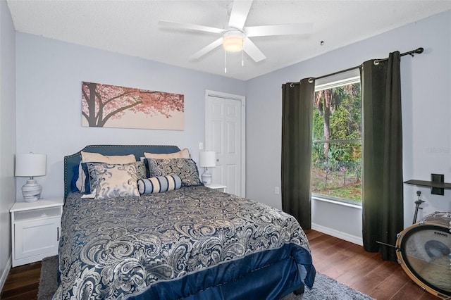 bedroom featuring a textured ceiling, baseboards, wood finished floors, and a ceiling fan