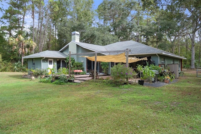 rear view of property with roof with shingles, a yard, and a chimney