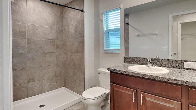 bathroom featuring vanity, toilet, and a tile shower