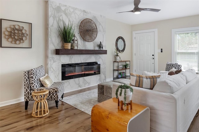 living room featuring ceiling fan, hardwood / wood-style flooring, and a fireplace