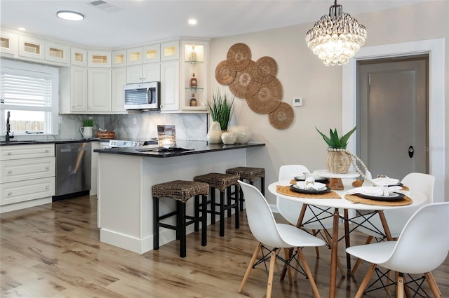 kitchen featuring white cabinetry, stainless steel appliances, light hardwood / wood-style flooring, and pendant lighting