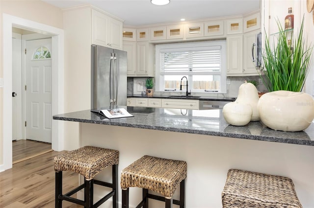 kitchen featuring tasteful backsplash, white cabinetry, hardwood / wood-style flooring, stainless steel refrigerator, and sink