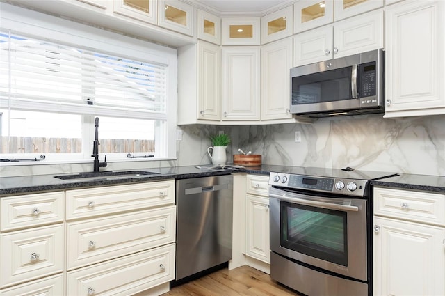 kitchen featuring appliances with stainless steel finishes, sink, light wood-type flooring, backsplash, and white cabinets