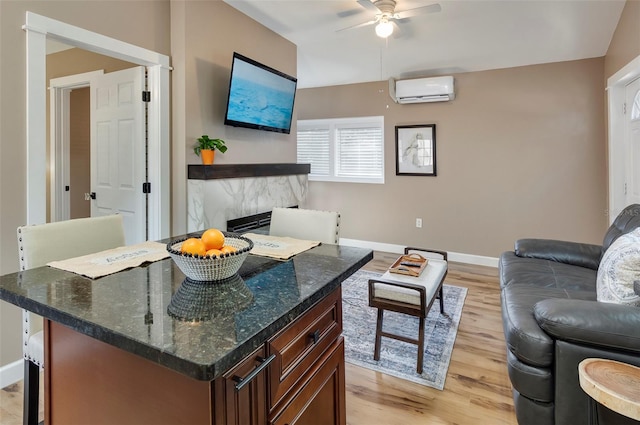 living room with a high end fireplace, a wall unit AC, light hardwood / wood-style floors, and ceiling fan