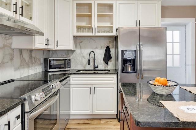 kitchen featuring appliances with stainless steel finishes, white cabinetry, light hardwood / wood-style floors, and dark stone countertops