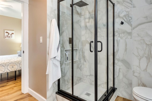 bathroom with a shower with door, toilet, and wood-type flooring