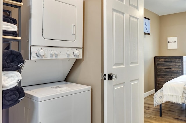 laundry area with stacked washer / dryer and light wood-type flooring