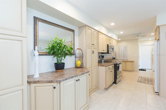 kitchen with appliances with stainless steel finishes, cream cabinets, light tile patterned floors, and ceiling fan