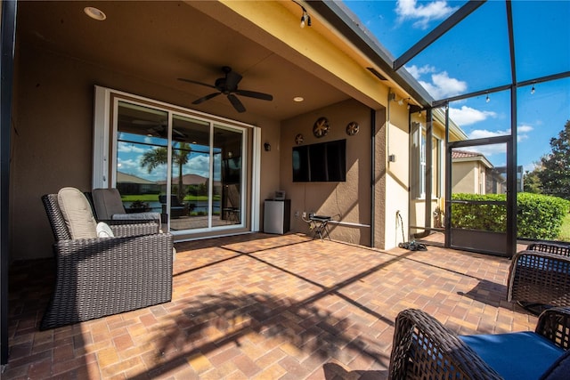 view of patio with ceiling fan and glass enclosure