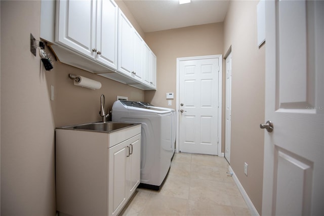 clothes washing area featuring light tile patterned floors, sink, separate washer and dryer, and cabinets