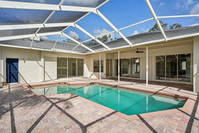 view of swimming pool with ceiling fan, a patio area, and glass enclosure