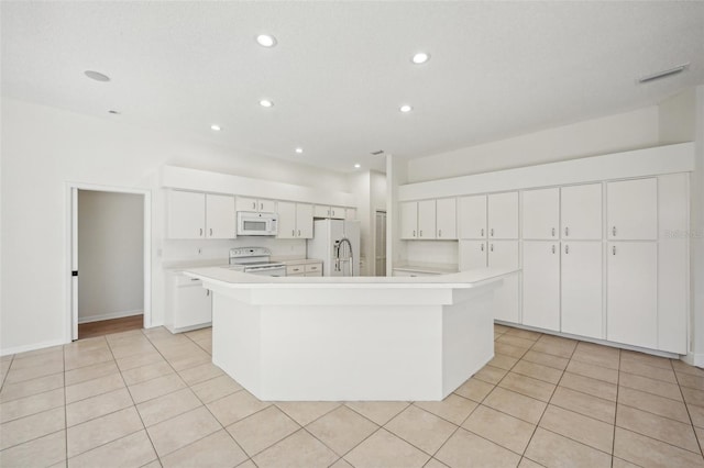 kitchen with white cabinetry, light tile patterned flooring, a spacious island, and white appliances