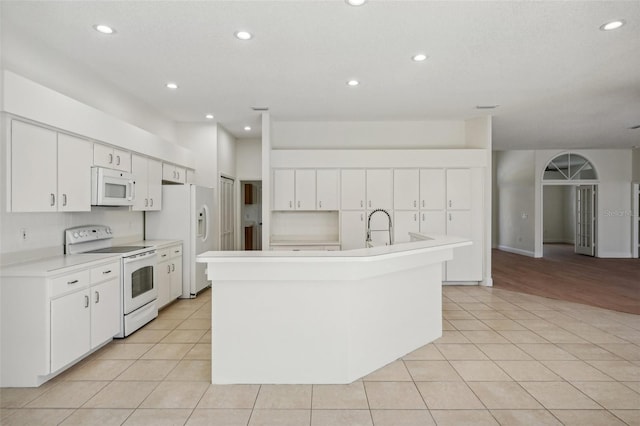 kitchen featuring white cabinetry, a kitchen island with sink, light tile patterned floors, and white appliances