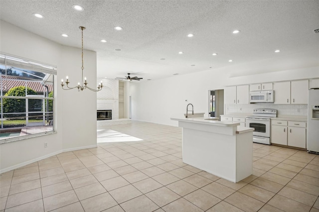 kitchen with ceiling fan with notable chandelier, white appliances, decorative light fixtures, white cabinetry, and light tile patterned flooring