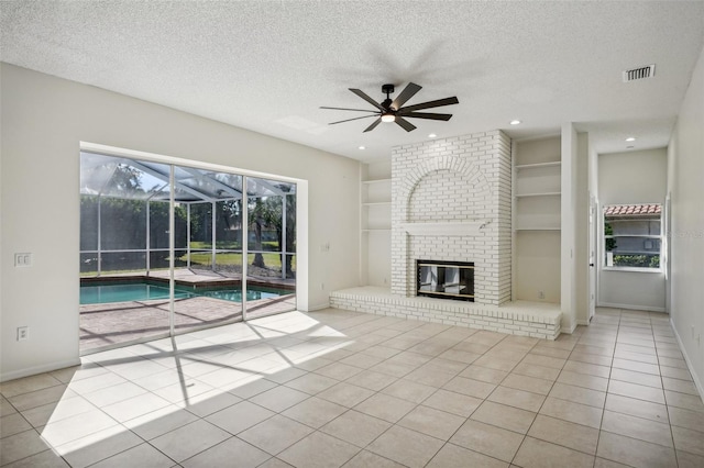 unfurnished living room featuring ceiling fan, built in features, a fireplace, and light tile patterned floors