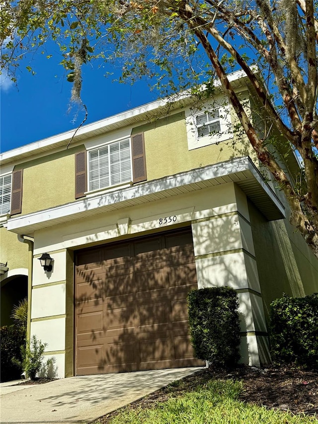 view of side of property with an attached garage, concrete driveway, and stucco siding