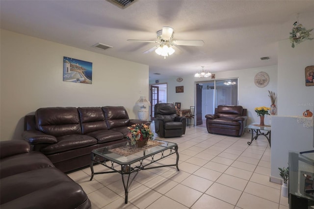 living room featuring ceiling fan with notable chandelier, light tile patterned flooring, and a textured ceiling