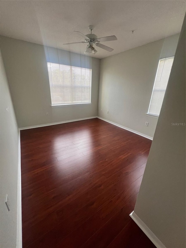 unfurnished room featuring dark wood-type flooring and ceiling fan