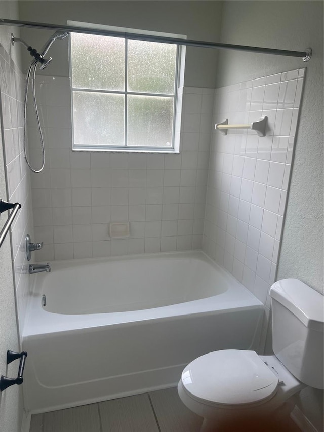 bathroom featuring toilet and tiled shower / bath combo