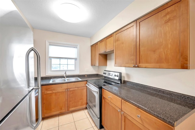 kitchen featuring dark stone countertops, sink, light tile patterned floors, appliances with stainless steel finishes, and a textured ceiling