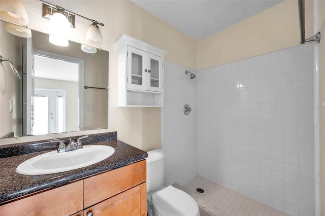 bathroom featuring vanity, a tile shower, and toilet