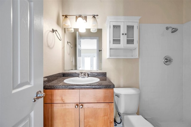 bathroom featuring vanity, toilet, and a tile shower