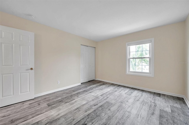 unfurnished bedroom with light hardwood / wood-style flooring and a closet