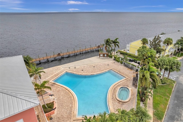 view of swimming pool featuring a hot tub, a patio area, and a water view