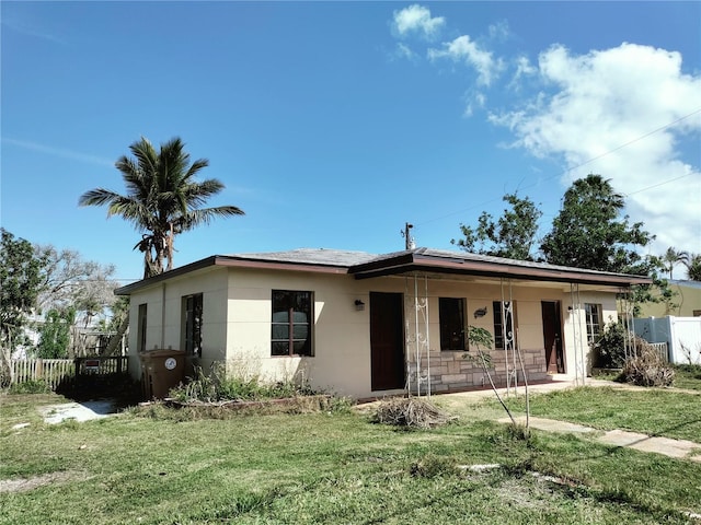 view of front of home featuring a porch, fence, a front lawn, and stucco siding