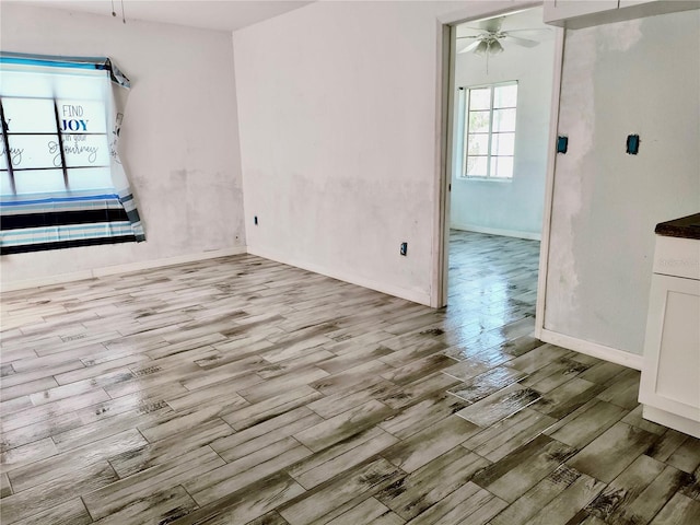 interior space with ceiling fan, wood finished floors, and baseboards