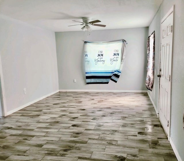 unfurnished room featuring wood finished floors, a ceiling fan, and baseboards