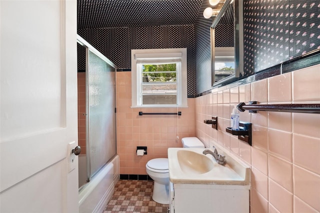 full bathroom featuring vanity, enclosed tub / shower combo, tile walls, and toilet