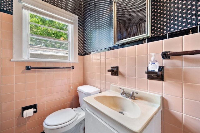 bathroom featuring vanity, toilet, and tile walls