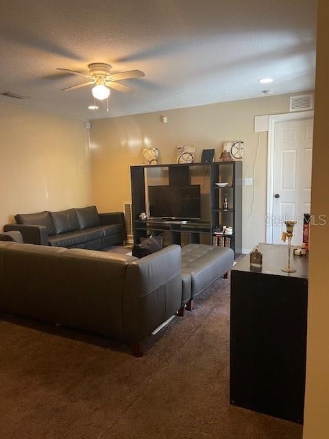 living room featuring ceiling fan and dark colored carpet