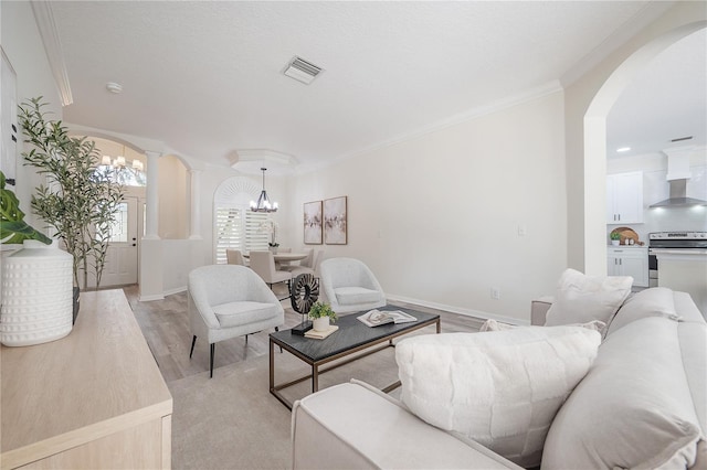 living room with light hardwood / wood-style flooring, a notable chandelier, and crown molding