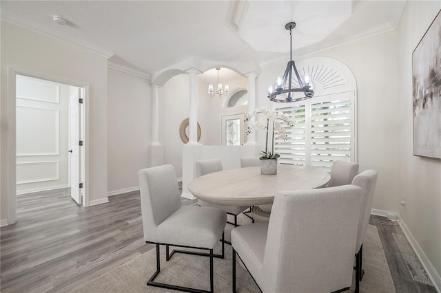 dining space with decorative columns, crown molding, and hardwood / wood-style flooring